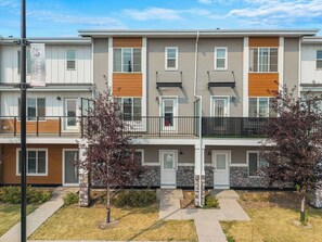 A multi-story residential building with a flat roof, balconies, and a stone facade. - King Bed | Close to Airport | 6 Guests (Calgary)