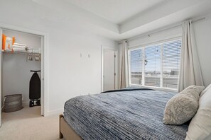 A bedroom with a bed, a closet with hanging clothes, and a window with blinds. - King Bed | Close to Airport | 6 Guests (Calgary)