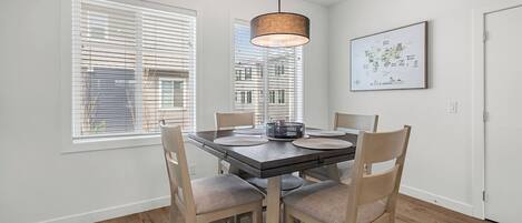 A dining area with a table, chairs, a hanging light fixture, and a wall-mounted map.
