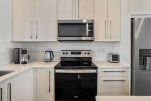 A modern kitchen with stainless steel appliances, including a microwave, coffee maker, and toaster. - King Bed | Close to Airport | 6 Guests (Calgary)