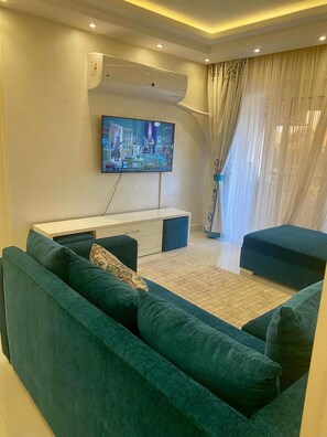 A living room with a flat-screen TV mounted on the wall, a sofa, and a coffee table. - Stylish & Cozy ~ 5* Location ~ King Beds ~ Balcony (Cairo)