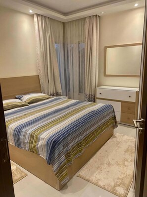 Ein Schlafzimmer mit Bett, Vorhängen, Nachttisch und Spiegel.