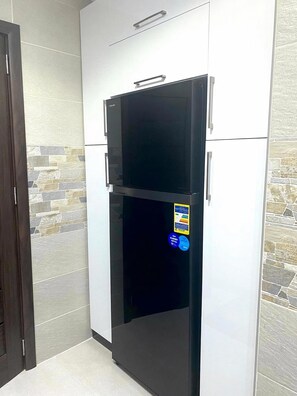 A black refrigerator in a kitchen with white cabinets and a stone backsplash. - Stylish & Cozy ~ 5* Location ~ King Beds ~ Balcony (Cairo)