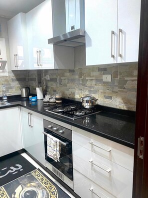 A modern kitchen with white cabinets, a gas stove, and a tiled backsplash. - Stylish & Cozy ~ 5* Location ~ King Beds ~ Balcony (Cairo)