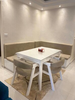 A corner seating area with a glass-top table, cushioned chairs, and a small table with a box on it. - Stylish & Cozy ~ 5* Location ~ King Beds ~ Balcony (Cairo)