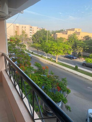 A balcony with a view of a street lined with trees and parked cars. - Stylish & Cozy ~ 5* Location ~ King Beds ~ Balcony (Cairo)
