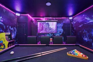 Ein Raum mit Billardtisch, Projektionsleinwand und Spielautomaten.