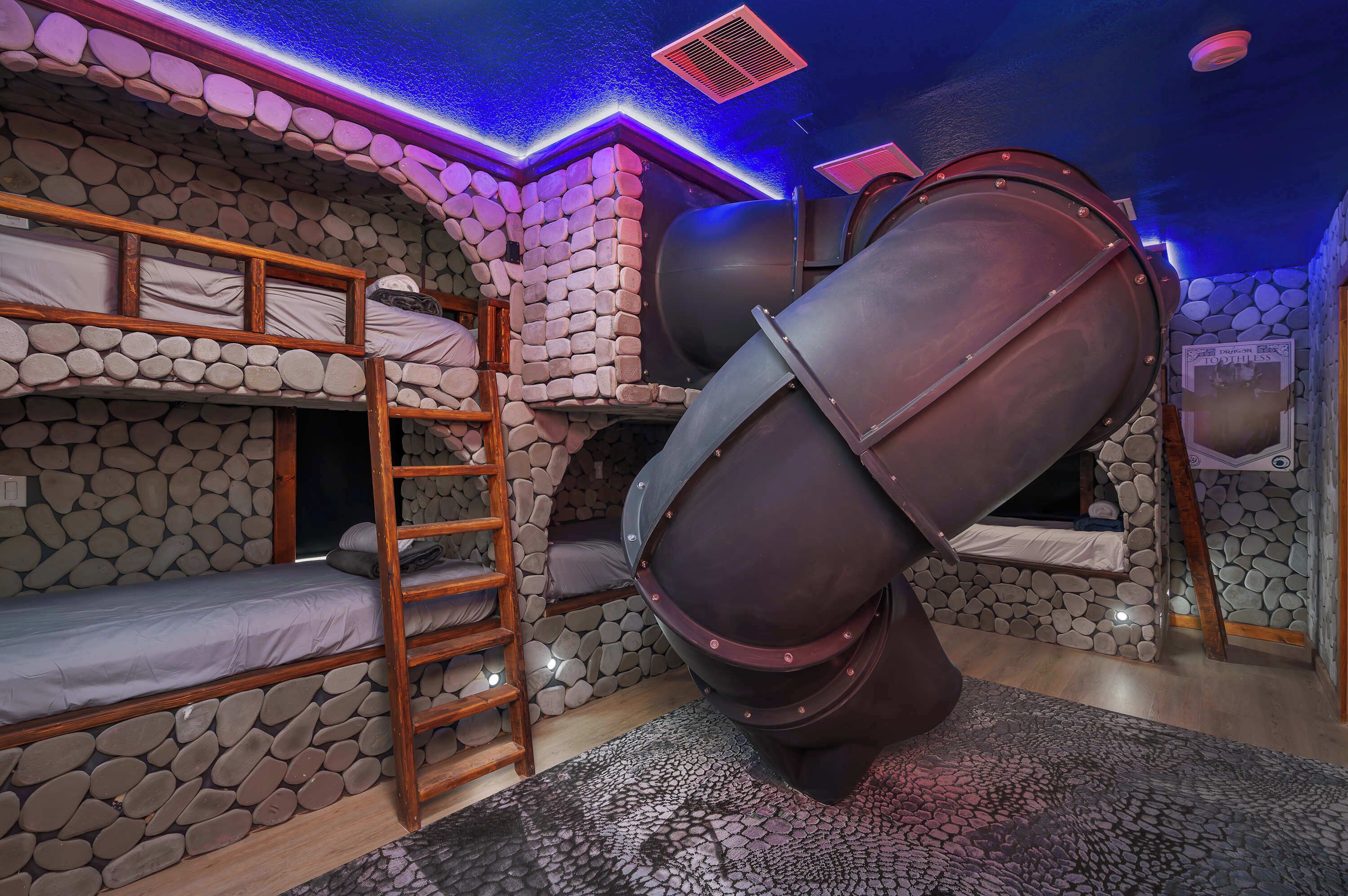 A bunk bed room with a stone wall, a ladder, and a large cylindrical object.
