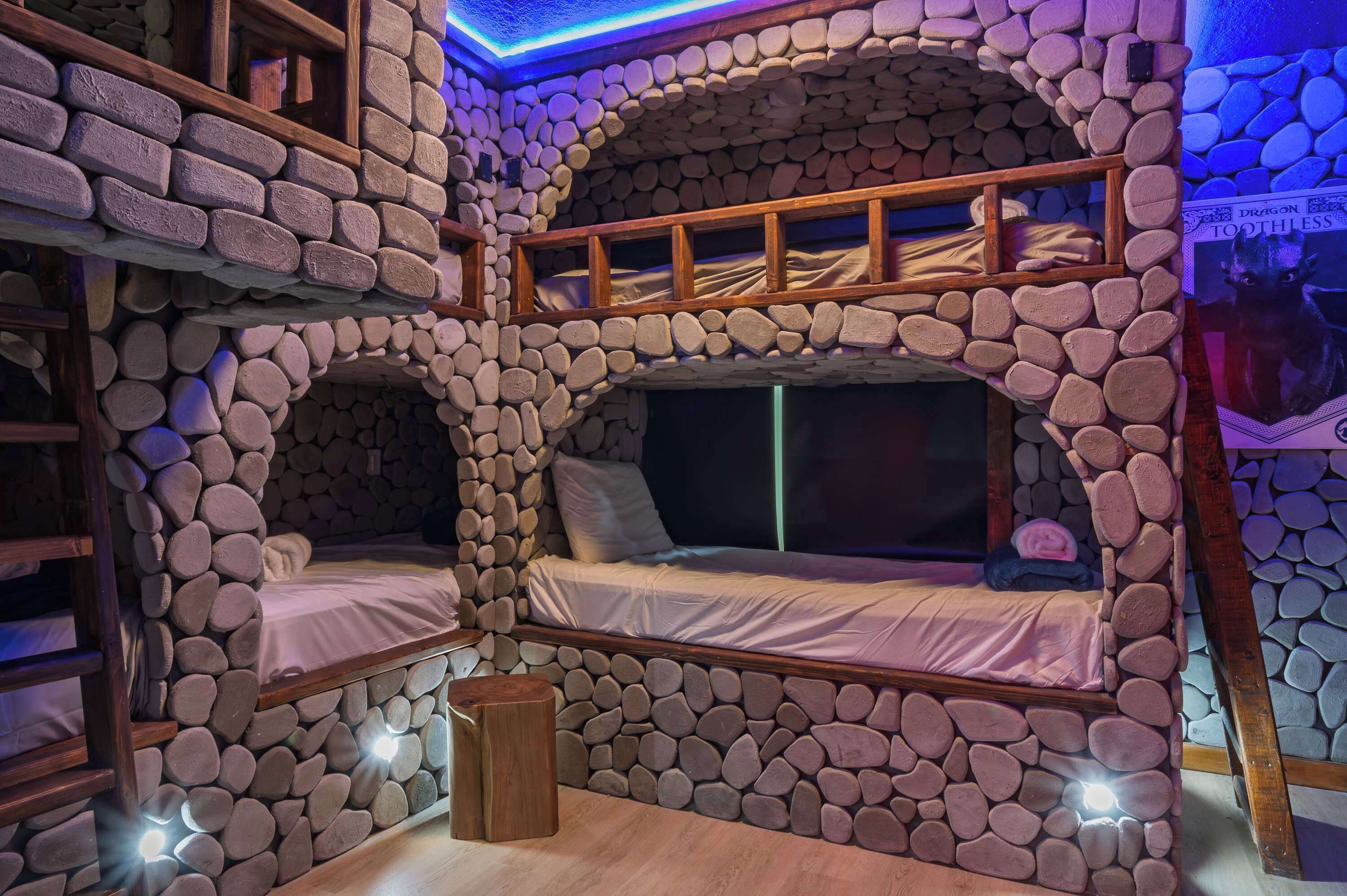 A room with a stone wall, a bunk bed, and a wooden ladder.
