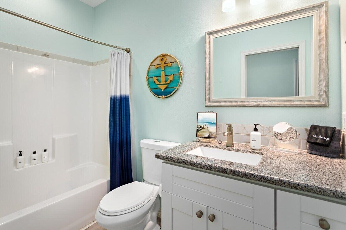 A bathroom with a bathtub, toilet, vanity with a mirror, and a towel rack.