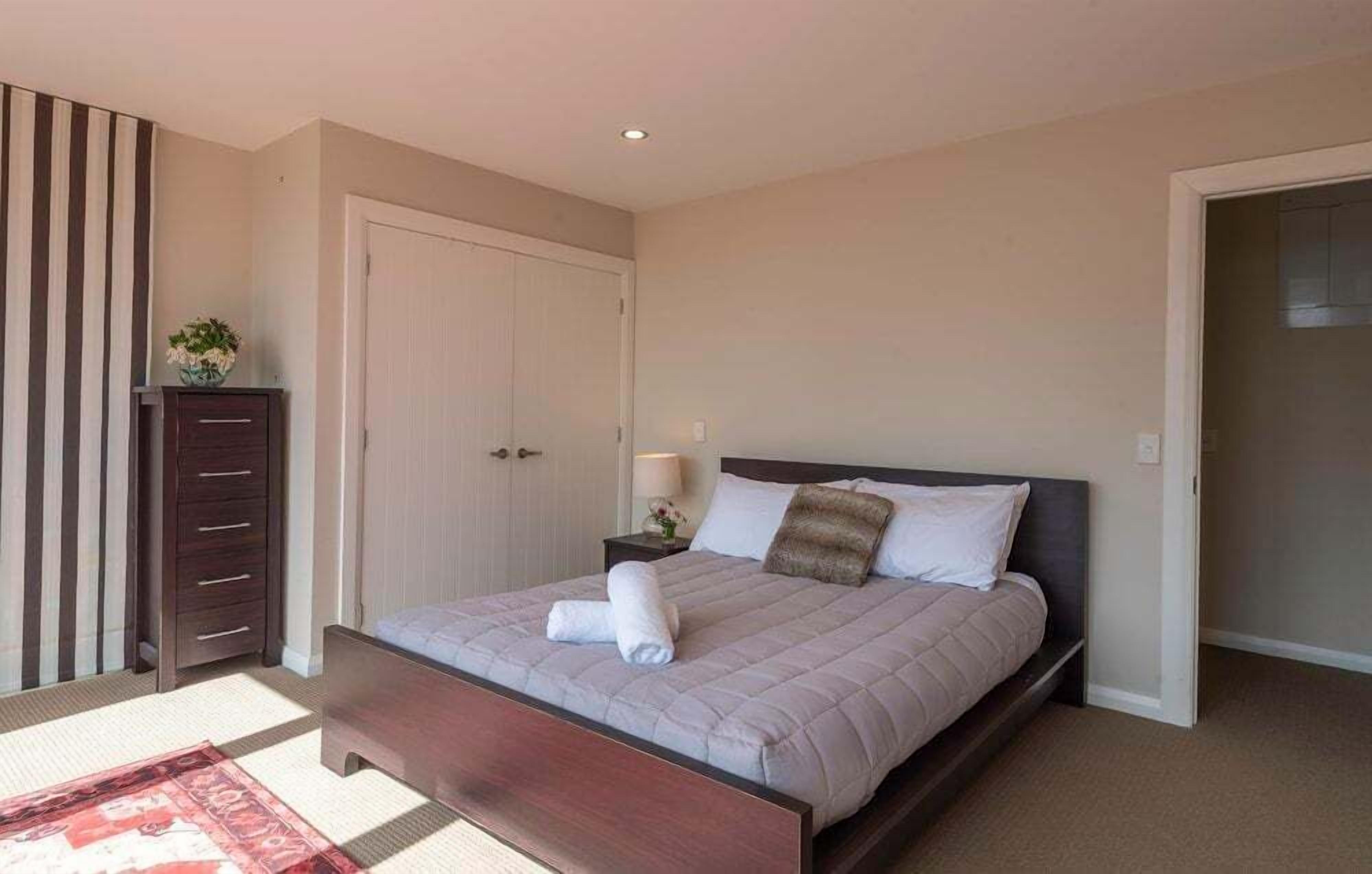A bedroom with a bed, bedside tables, a wardrobe, and a door.