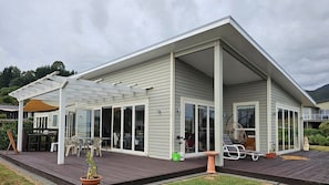 A modern house with a covered patio, large sliding glass doors, and outdoor furniture.