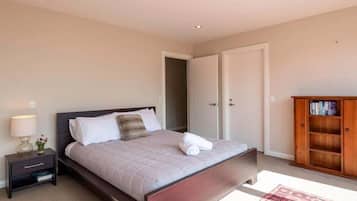 Ein Schlafzimmer mit Bett, Nachttisch, Lampe und einem Holzschrank.