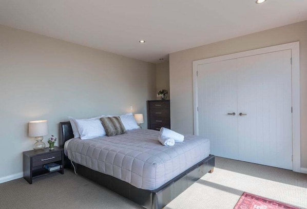 A bedroom with a bed, nightstand, dresser, and a door.