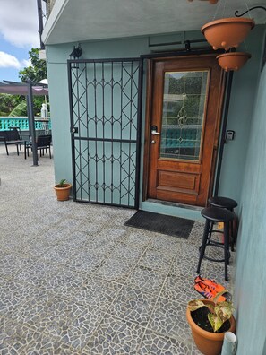 Ein verschlossener Eingang mit einer Holztür, einer gefliesten Terrasse und Sitzgelegenheiten im Freien.