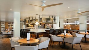 Ein modernes Restaurant mit runden Tischen, einer Bar und einer zentral gelegenen Bar-Ecke.