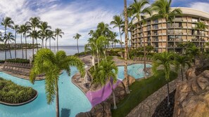 Ein Resort mit mehreren Swimmingpools, Palmen und Blick auf den Strand.