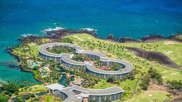 Ein Resort mit kreisförmiger Bebauung, umgeben von üppiger Vegetation und einem Golfplatz.