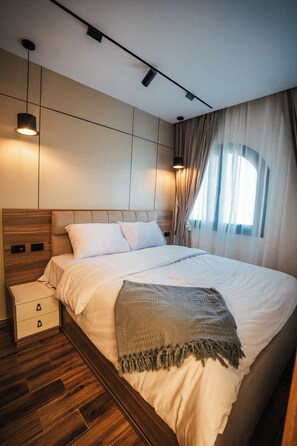 A modern bedroom with a large bed, wooden headboard, and a bedside table with drawers. - Blue Haven H 101 Nubian The view Hurghada (hurghada)