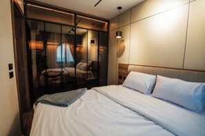 Une chambre moderne avec un grand lit, une cloison en verre et une tête de lit en bois.