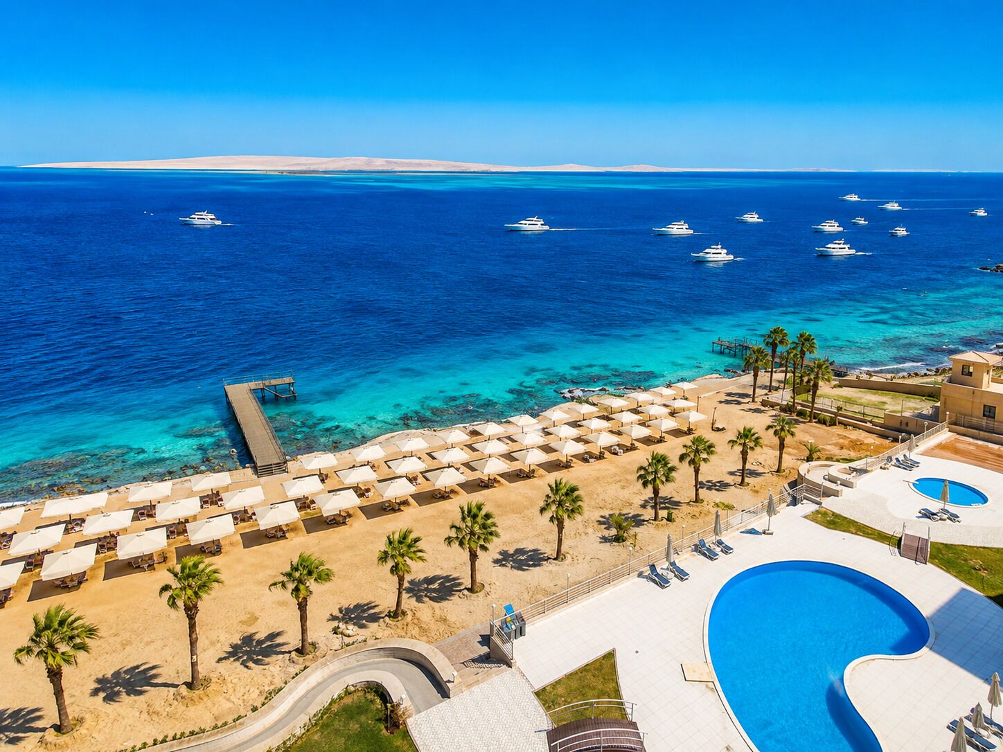 A resort with a pool, beach area, and ocean view.