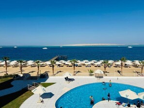 A pool area with a view of the sea, beach umbrellas, and lounge chairs. - Blue Haven H 101 Nubian The view Hurghada (hurghada)