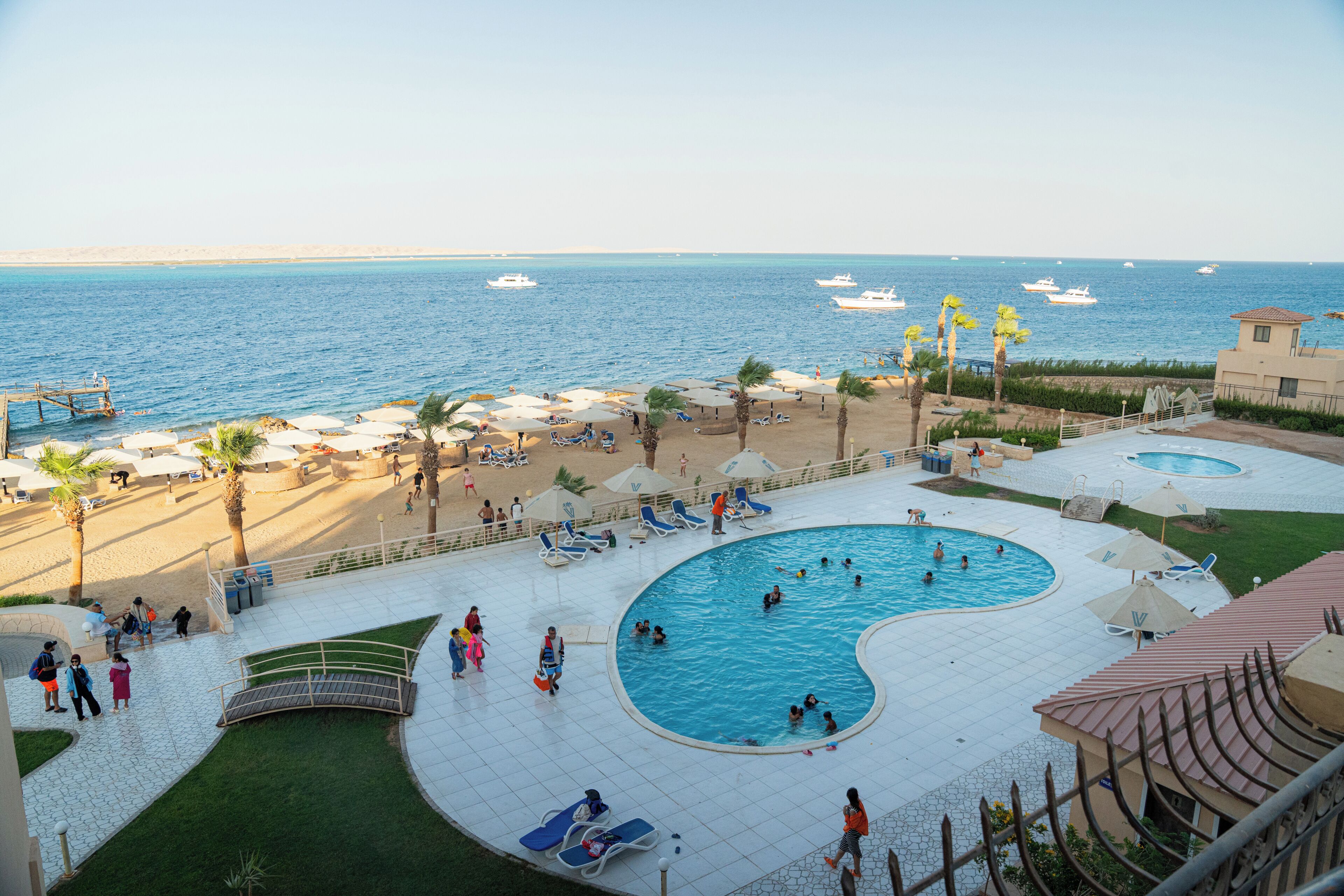 A resort pool area with multiple swimming pools, sun loungers, and beach umbrellas.