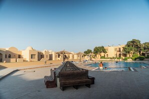 A pool area with lounge chairs and a wooden bench. - Blue Haven H 101 Nubian The view Hurghada (hurghada)