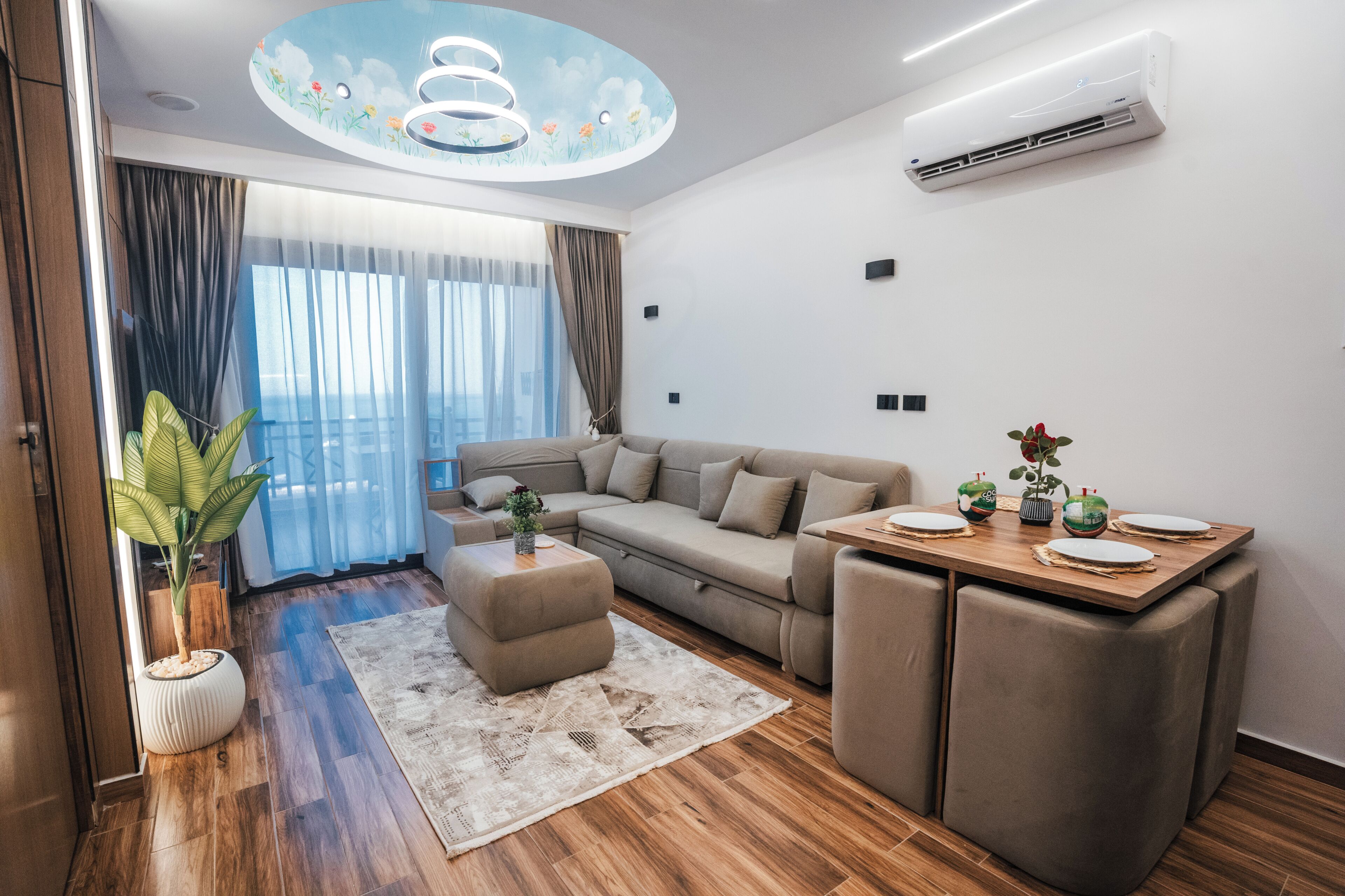 Una sala de estar moderna con un sofá, una mesa de centro y un comedor con una mesa dispuesta para dos.