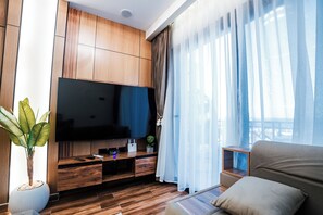 Un salon moderne avec un téléviseur à écran plat, un meuble de rangement en bois, une plante en pot et un canapé.