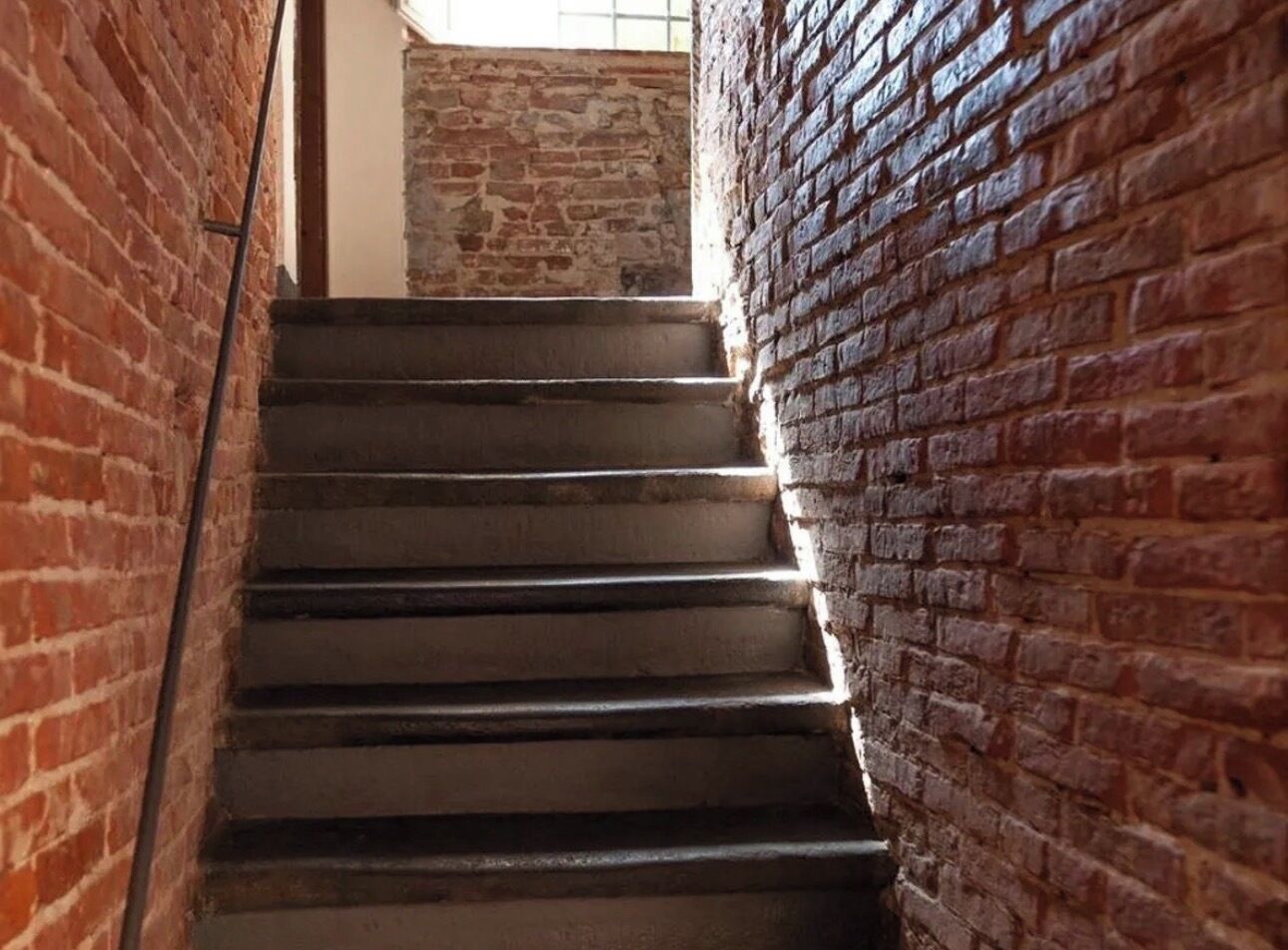 A staircase with a brick wall on one side and a metal railing on the other.