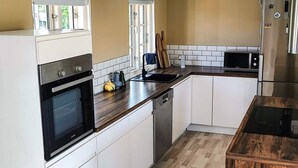 Una cocina moderna con armarios blancos, un horno negro, un microondas y un refrigerador de acero inoxidable.