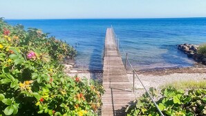 Un muelle de madera se adentra en aguas azules y tranquilas, rodeado de exuberante vegetación y rocas.