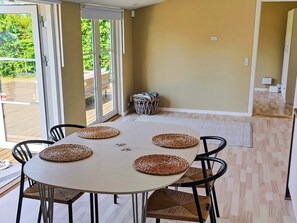 A dining area with a round table, four chairs, and woven placemats. - 4 Star Holiday Home in Stroby (Strøby)