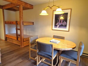 Ein Zimmer mit einem Holzbett, einem runden Tisch mit Stühlen und einem gerahmten Bild an der Wand.