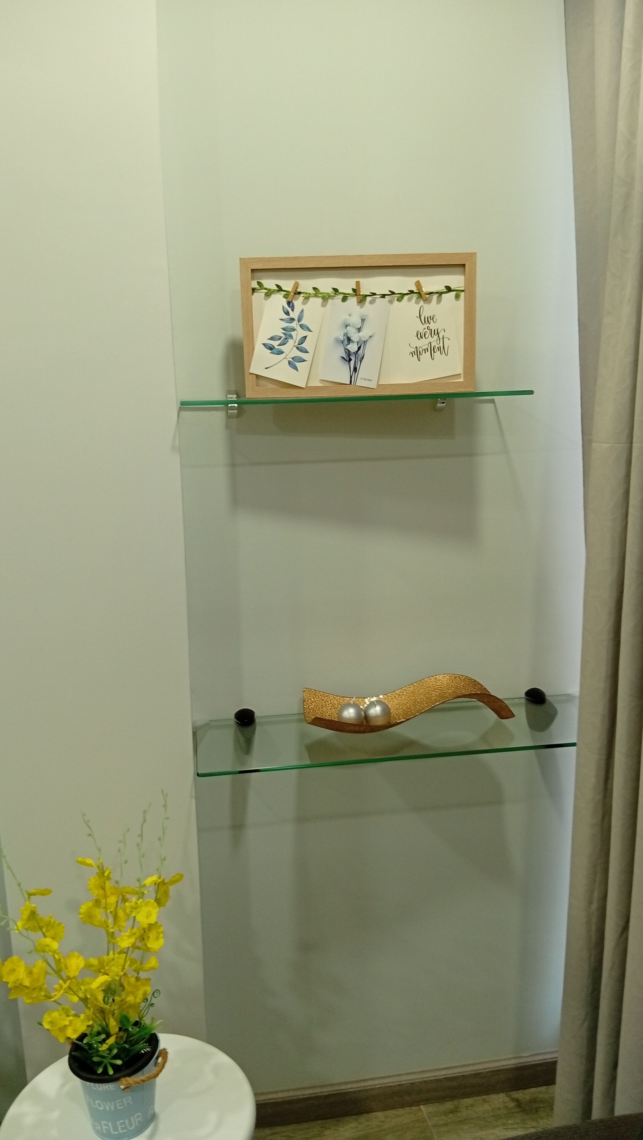 A wall-mounted shelf with a framed picture, a small potted plant, and a decorative item.