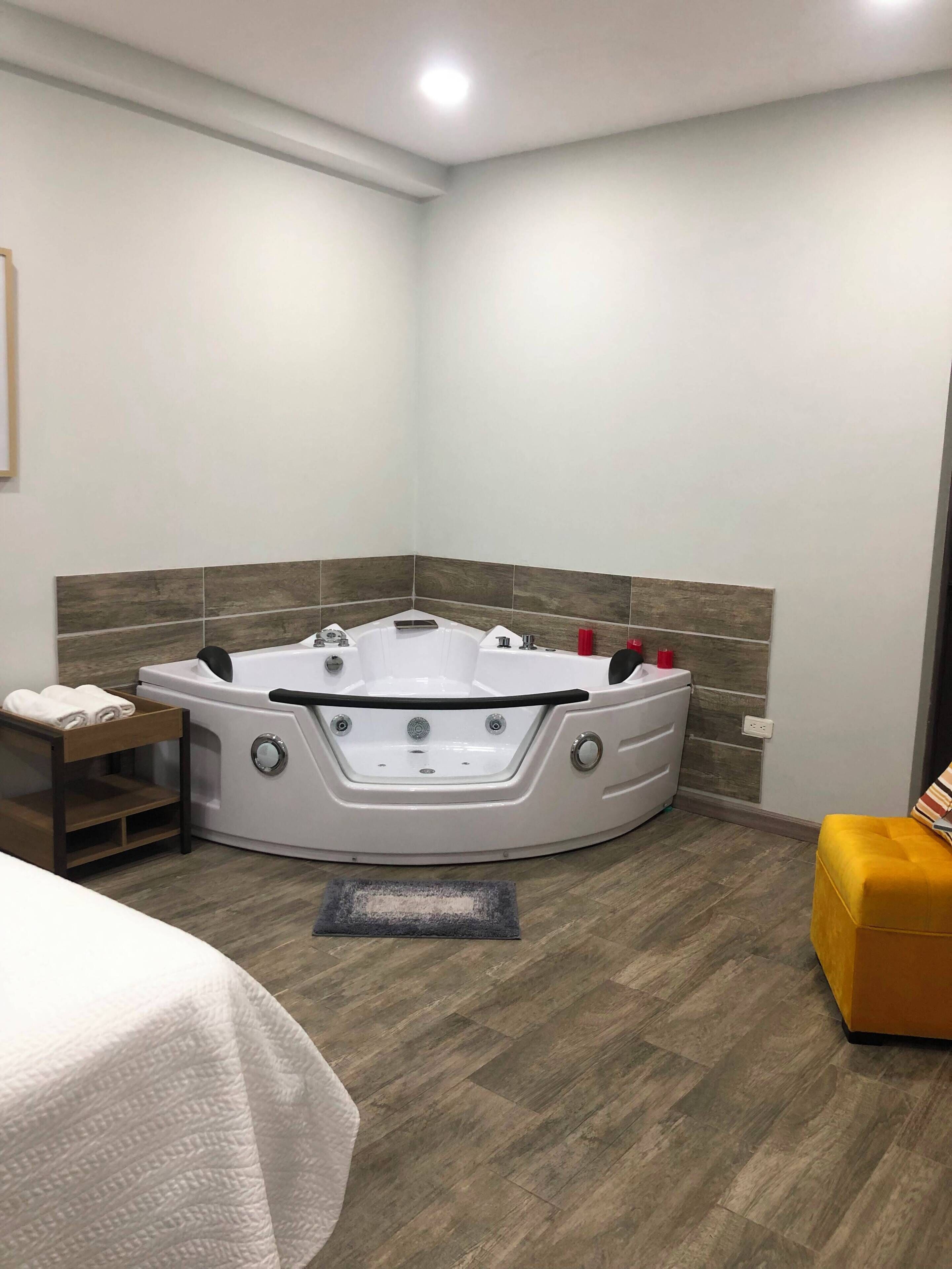 Un baño moderno con una bañera independiente, un banco de madera y un otoman amarillo.