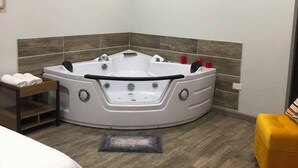 A modern bathroom with a freestanding bathtub, a wooden bench, and a yellow ottoman.