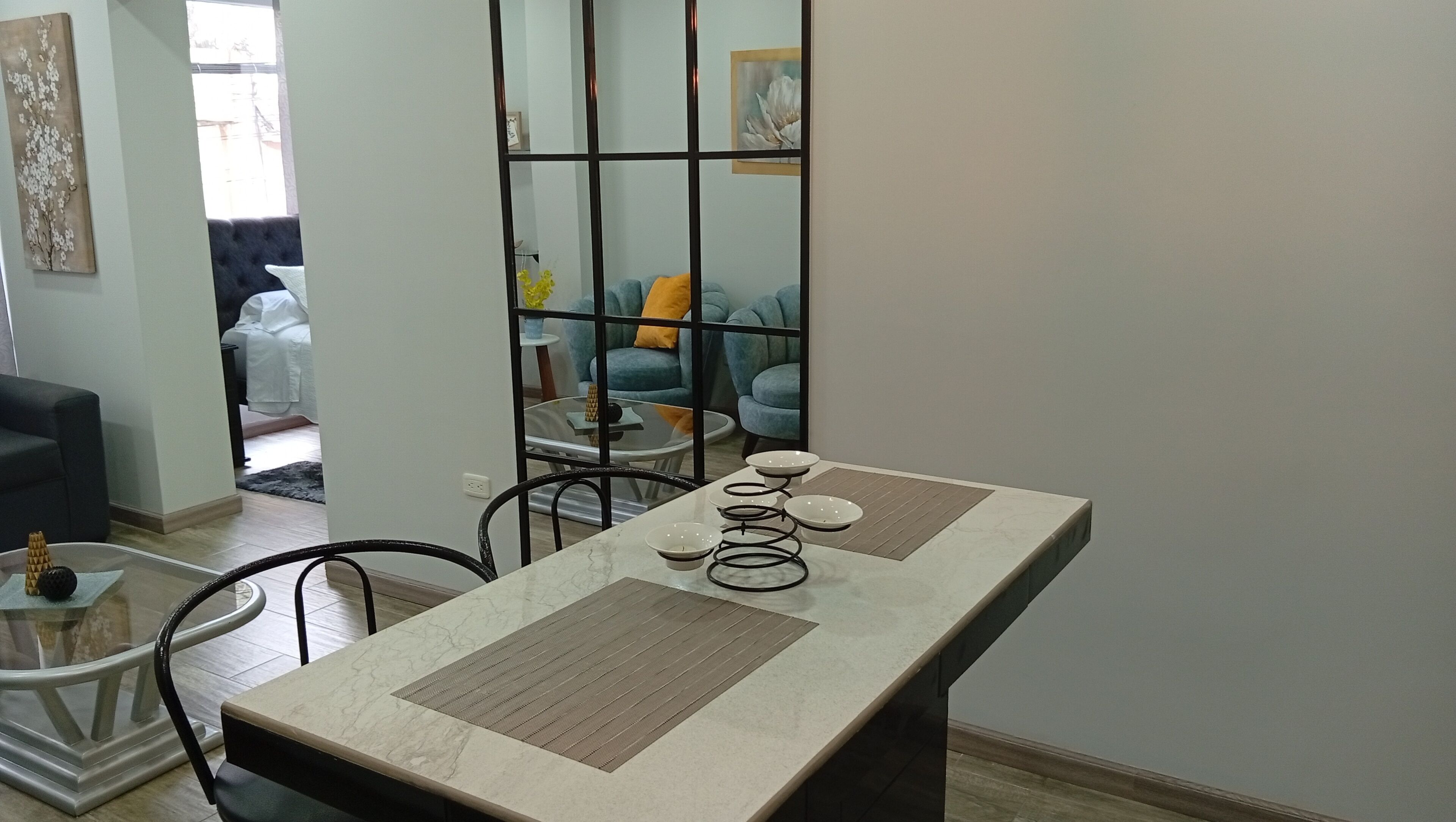 A dining area with a marble table, chairs, and a decorative mirror.