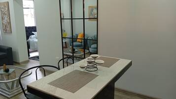 A dining area with a marble table, chairs, and a decorative mirror.