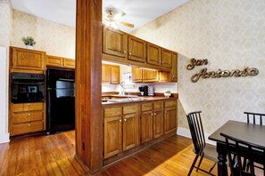 Eine Küche mit Holzschränken, einem Kühlschrank und einem Essbereich mit einem Stuhl.