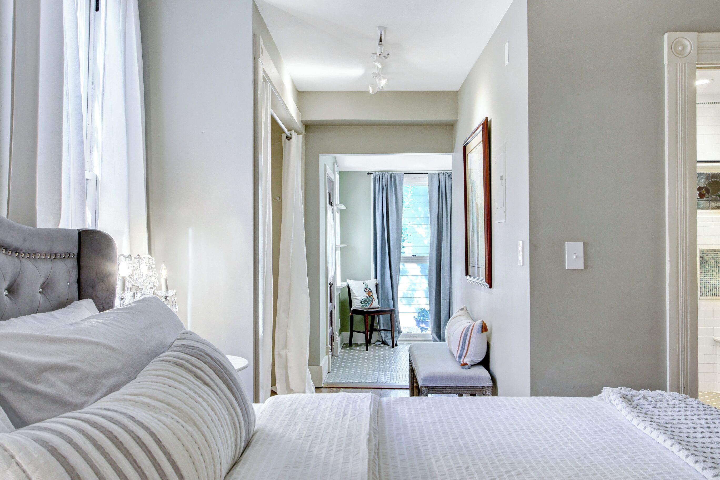 A hotel room with a large bed, a chair, a desk, and a view of the outside.