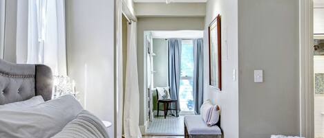 A hotel room with a large bed, a chair, a desk, and a view of the outside.