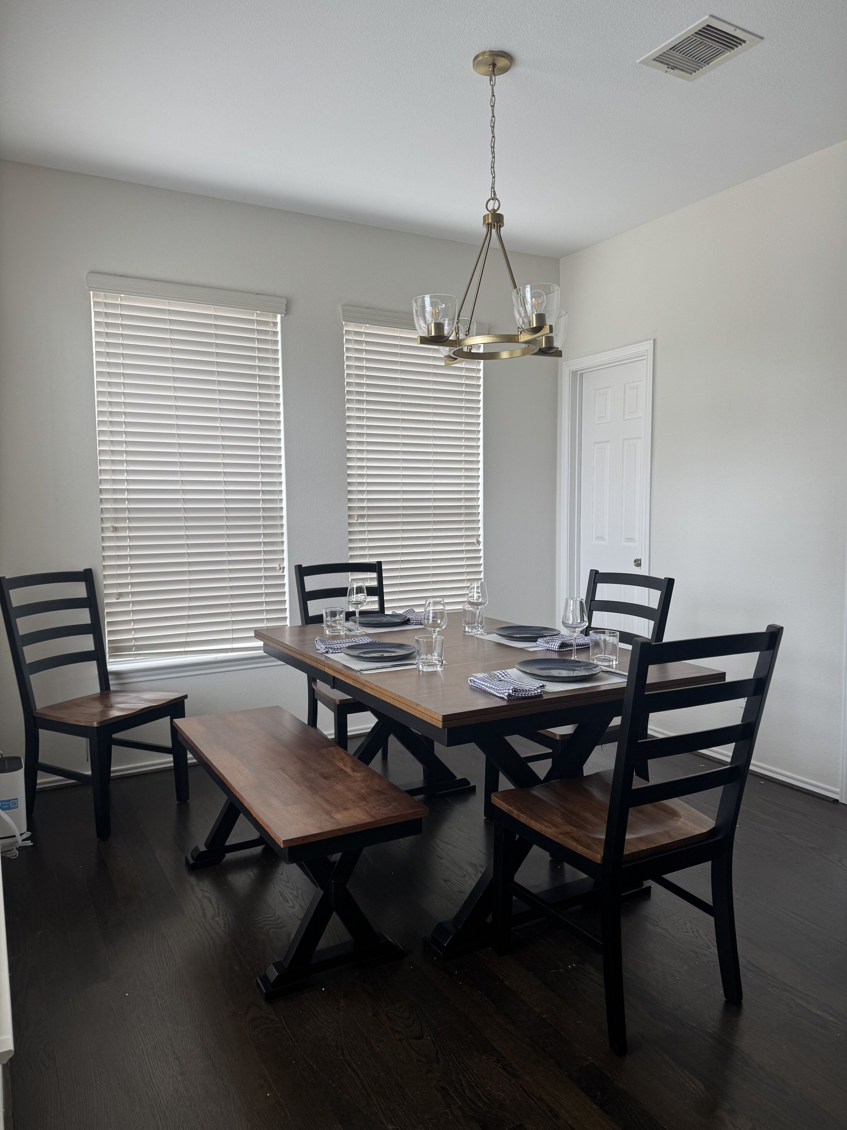 Un comedor con una mesa de madera, cuatro sillas y una araña.