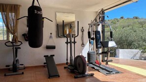 A home gym with exercise equipment, a punching bag, and a mirror. - Casa Pil Riogordo by Ruralidays (Málaga)