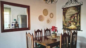 A dining area with a wooden table, chairs, a mirror, and a painting on the wall. - Casa Pil Riogordo by Ruralidays (Málaga)