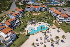 Un resort con varias edificaciones, una piscina central y acceso directo a la playa.