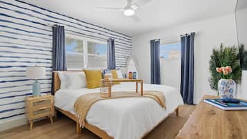 A bedroom with a bed, bedside tables, a ceiling fan, and a window with curtains.
