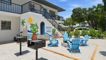 A building with a mural, outdoor seating, and a barbecue grill.