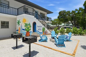 A building with a mural, outdoor seating, and a barbecue grill.